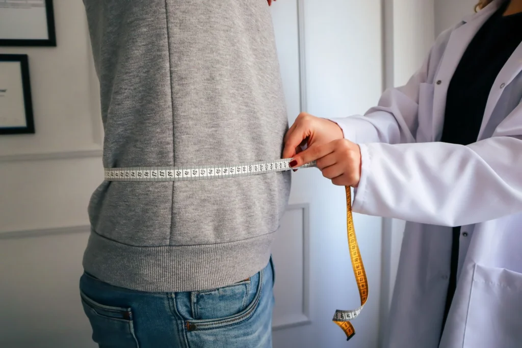 Médecin mesurant le tour de taille d'un patient lors d'une consultation