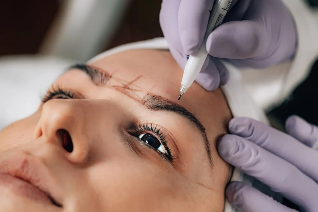 Praticienne gantée travaillant sur des sourcils en maquillage permanent