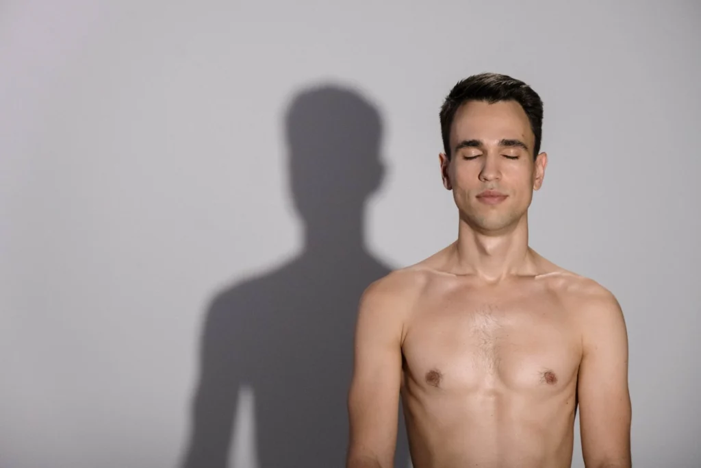Homme torse nu, les yeux fermés, sur fond gris