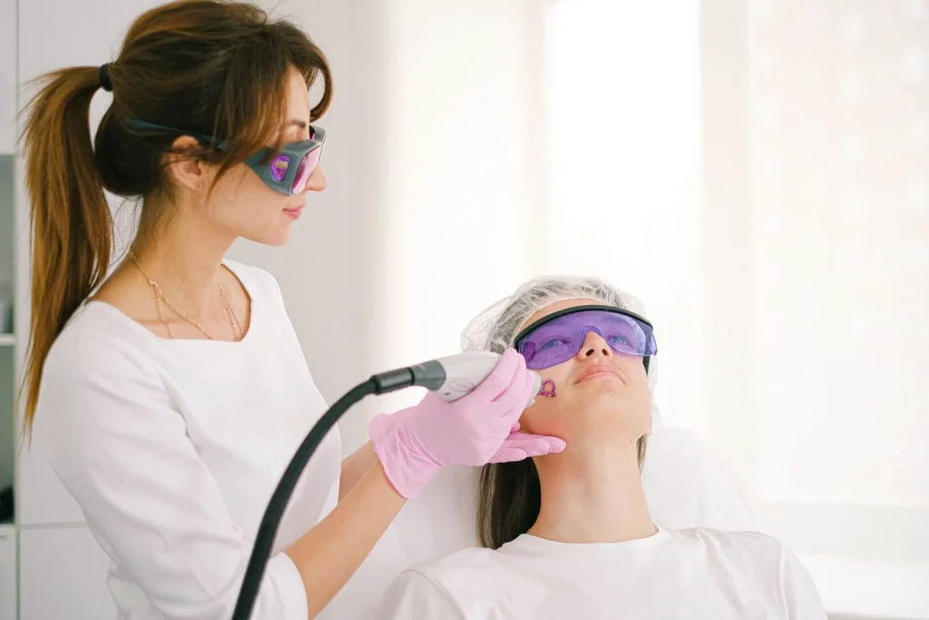 Praticienne et patiente portant des lunettes de protection pendant une séance de laser sur le visage