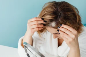Femme écartant ses cheveux pour observer sa raie et son cuir chevelu