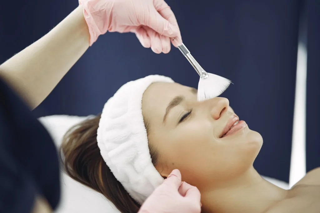 Application d'un peeling au pinceau sur le visage d'une patiente